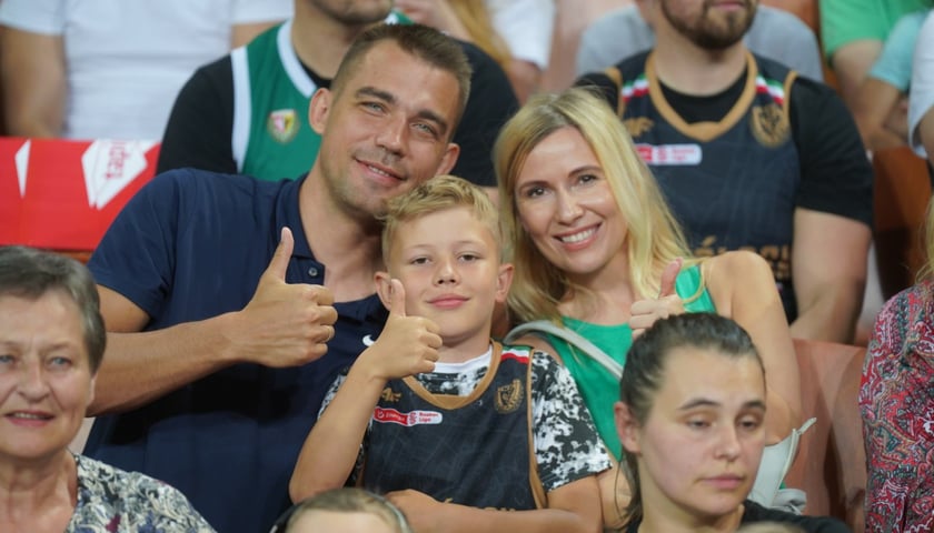 Uśmiechnięci kibice w Hali Stulecia na meczu z Treflem: kobieta, mężczyzna i chłopiec