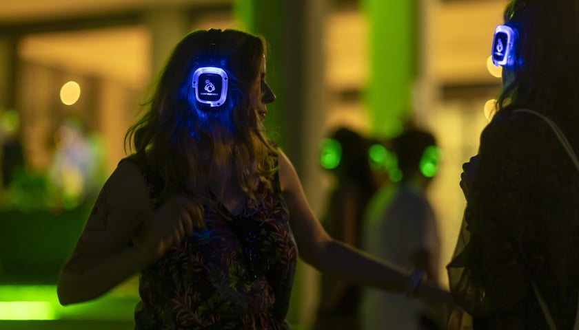 Silent disco we Wrocławiu 2023 - kobieta ze świecącymi słuchawkami na uszach tańczy