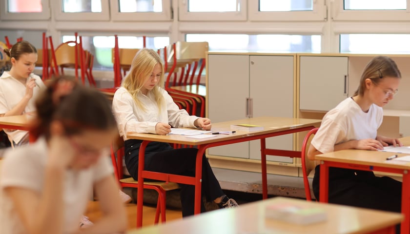 Ósmoklasiści piszący egzamin z j. polskiego, zdjęcie ilustracyjne