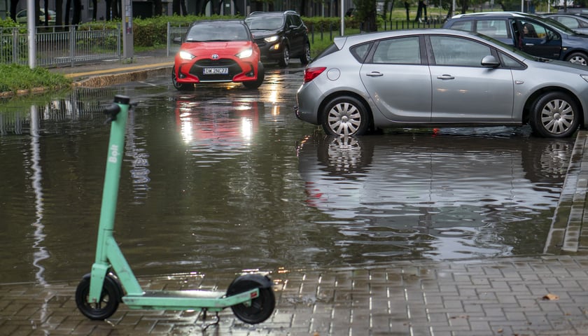 Ulewa we Wrocławiu. Samochody przejeżdżający przez zalaną ulicę, hulajnoga w kałuży