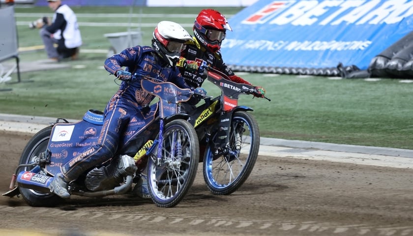 Dwaj żużlowcy (kaski biały i czerwony) jadący obok siebie na torze Olimpijskiego podczas meczu Sparty Wrocław ze Stalą Gorzów 