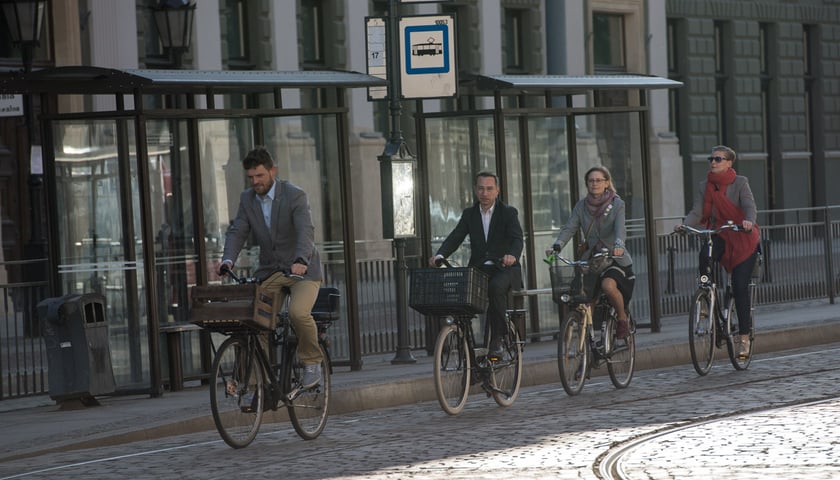 Dwóch mężczyzn i dwie kobiety jadący na rowerach, po torowisku przy przystanku Opera we Wrocławiu.