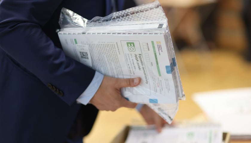 Zbliżenie na dłonie i arkusze egzaminu ósmoklasisty/ zdjęcie archiwalne