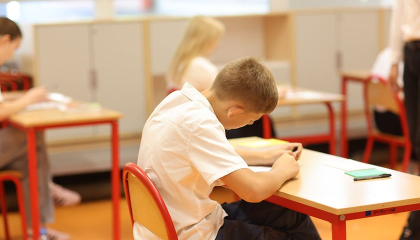 Uczeń siedzący w ławce podczas egzaminu ósmoklasisty w SP nr 29