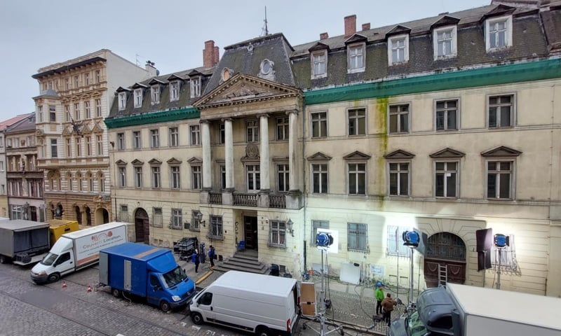 Pałac przy Szajnochy, zaparkowane na ulicy samochody techniczne ekipy filmowej