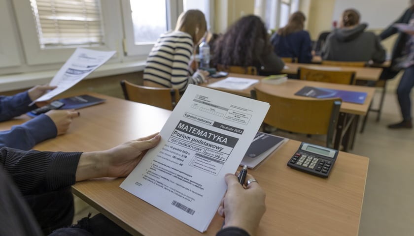 Matura próbna z matematyki z CKE w XV LO we Wrocławiu. Na pierwszym planie arkusz egzaminacyjny i dłonie. Zdjęcie archiwalne