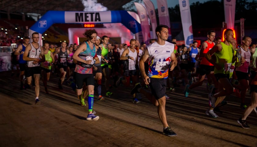 Uczestnicy 9. Nocnego Półmaratonu we Wrocławiu. Na zdjęciu widać grupę biegnących osób w strojach sportowych 
