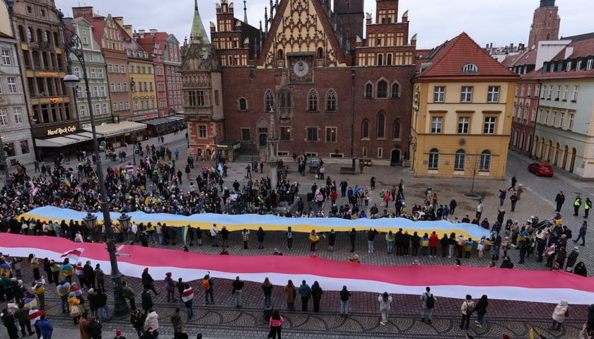 Luty 2023. Uroczystości we wrocławskim Rynku będące wyrazem solidarności Polaków z Ukraińcami. Widok z góry na ludzi trzymających flagi polską i ukraińską.
