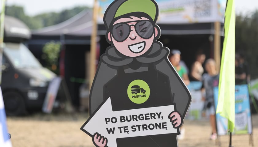 Ludzik wskazujący strefę gastronomiczną na Festiwalu Pasibrzucha 2024