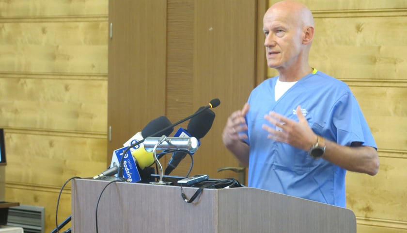 Mężczyzna za mównicą w niebieskiej bluzie lekarskiej. Prof. Tomasz Wróbel, kierownik Kliniki Hematologii, Terapii Komórkowych i Chorób Wewnętrznych UMW.