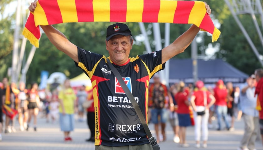 Kibic Sparty z czerwono-żółtym szalikiem w górze przed stadionem Olimpijskim  