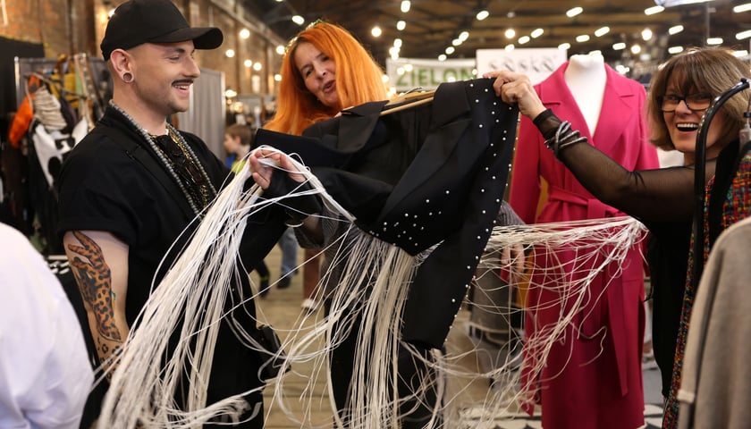 Na zdjęciu ludzie oglądający designerskie ubranie podczas Targów Kupuj Świadomie