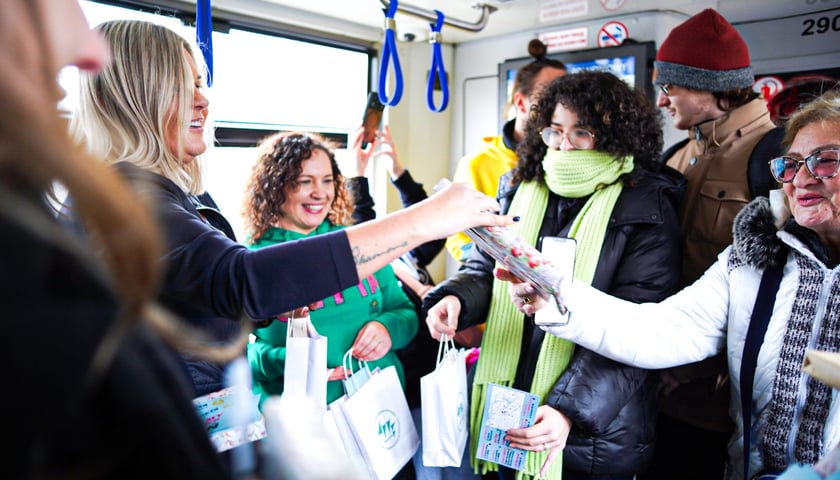 Ludzie w tramwaju, w którym wręczane są książki