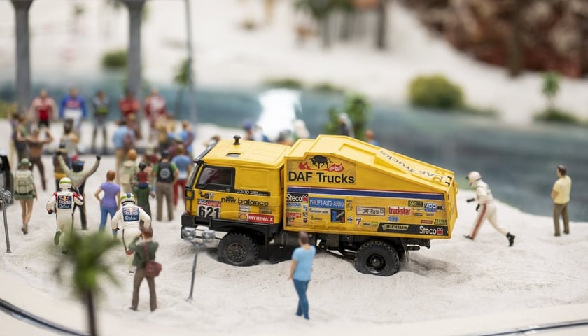 Powiększ obraz: Na miniaturowej makiecie Kolejkowo pojawiło się „Miasto Dakar” - na zdjęciu żółta ciężarówka rajdowa DAF 3300 otoczona przez figurki kibiców na pustynnym piasku