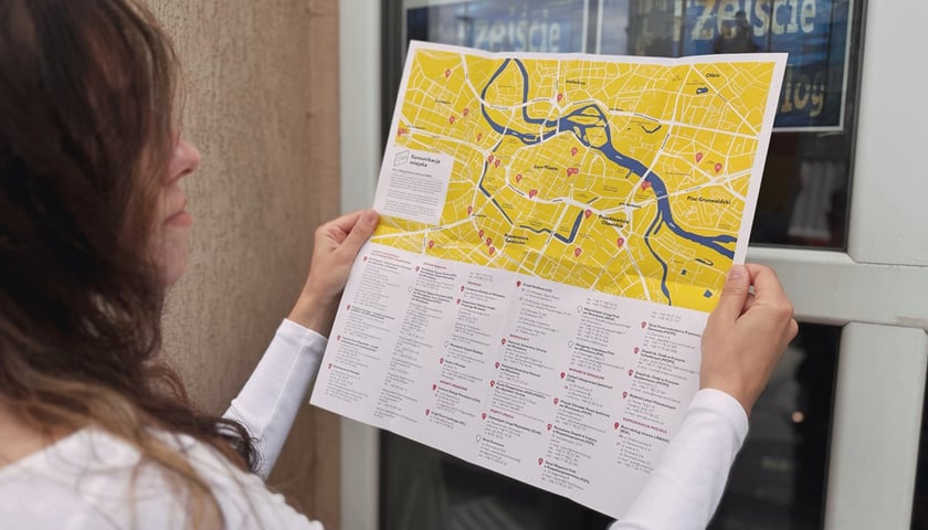 Powiększ obraz: Kobieta trzyma w dłoniach żółtą mapę - przewodnik po mieście