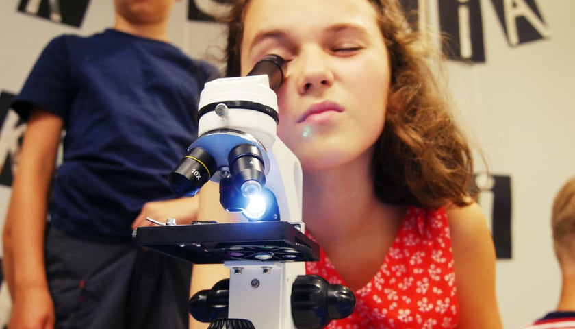 Powiększ obraz: Dziewczynka patrząca w mikroskop