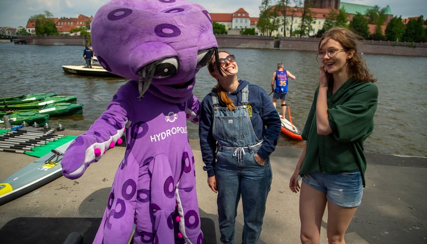 Powiększ obraz: Maskotka Hydropolis (Ośmiornica) z dwoma dziewczynami na bulwarze Dunikowskiego, Dzień Odry 2022