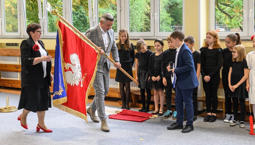 Powiększ obraz: <p>Uroczystości nadania imienia Szkole Podstawowej nr 4 we Wrocławiu &ndash; Jarosław Delewski, dyrektor Departamentu Edukacji przekazuje sztandar dyrektorce&nbsp;Teresie Bartnickiej-Romanowskiej&nbsp;</p>