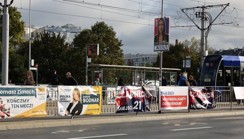 Powiększ obraz: Plakaty wyborcze na ogrodzeniu przystanku