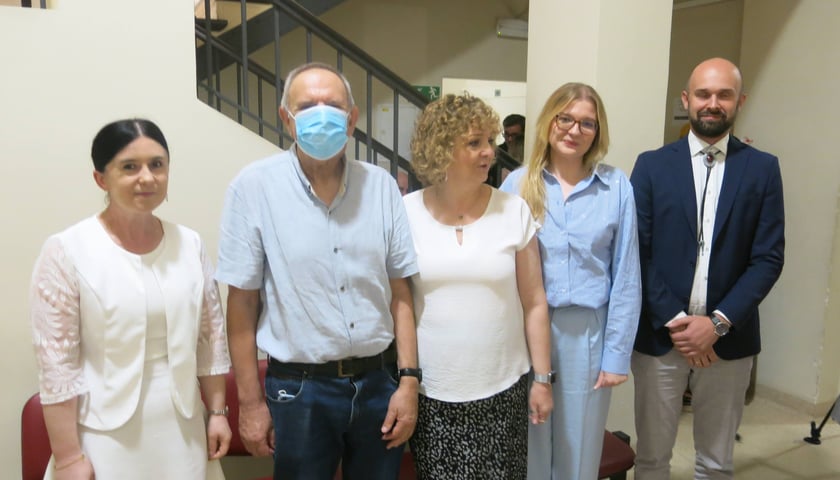 Grupa stojących ludzi. Jan Kowalski (w maseczce) i zespół z RCKiK w Poznaniu, który modyfikował jego limfocyty.