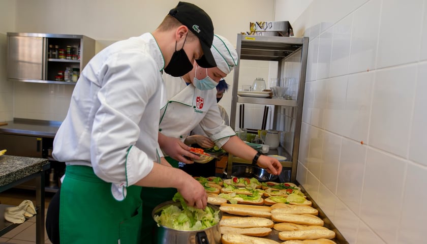Powiększ obraz: uczniowie z Zespołu Szkół Gastronomicznych oraz Technikum nr 16 przygotowują kanapki dla oczekujących na Dworcu Głównym