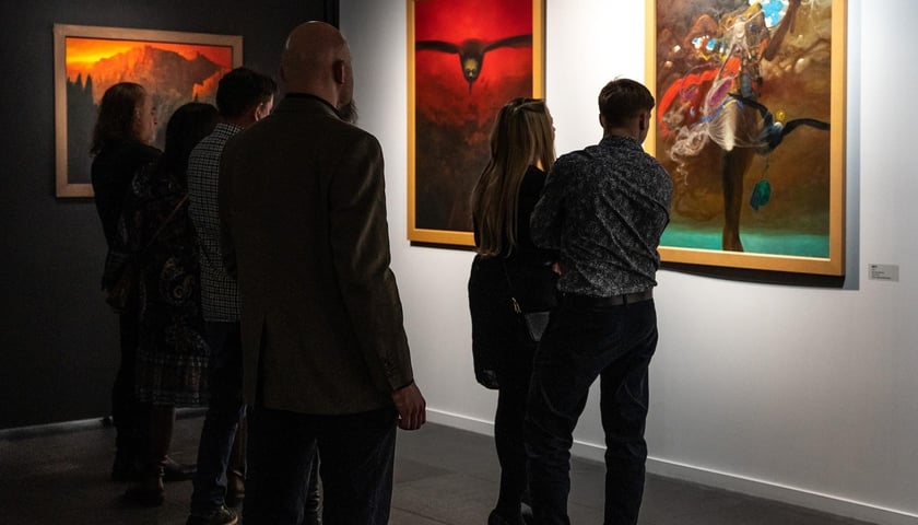 Grupa ludzi oglądająca obraz Zdzisława Beksińskiego 