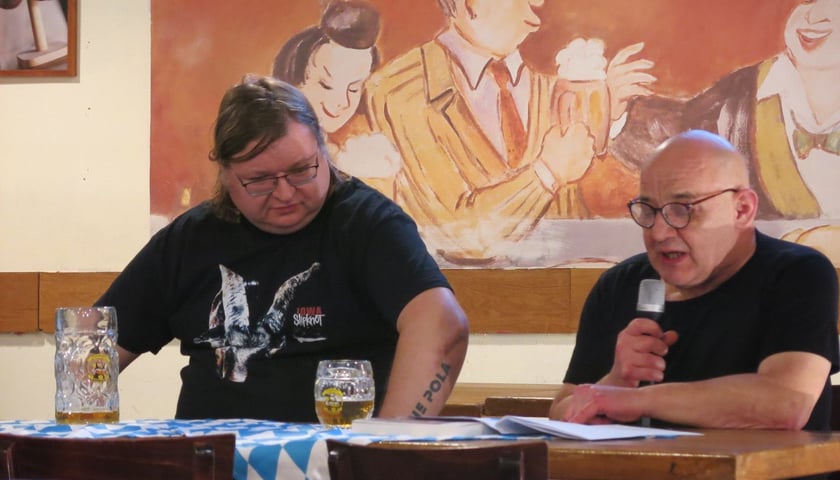 <p>Przemysław Wojcieszek podczas spotkania autorskiego, obok Jacek Zawadzki czyta fragmenty powieści &bdquo;Świnie wojny&rdquo;</p>