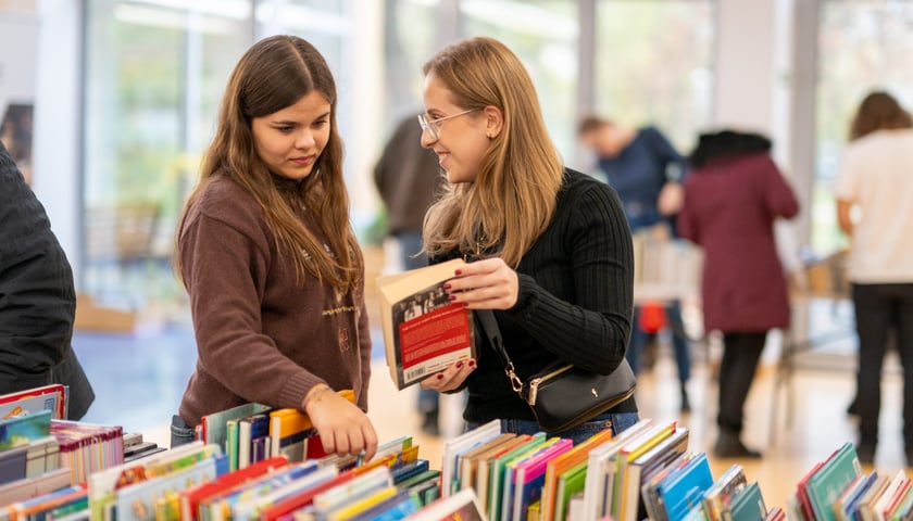 Zdjęcie ilustracyjne: 2 kobiety wybierające książkę w bibliotece