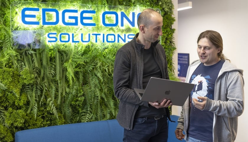 Dwóch mężczyzn z komputerem. Pracownicy Edge One Solutions  we Wrocławiu 