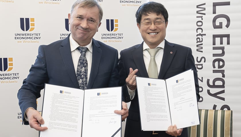 Dwóch uśmiechniętych mężczyzn, trzymają w rękach dokumenty. prof. dr hab. Czesław Zając, rektor Uniwersytetu Ekonomicznego we Wrocławiu i  Jangha Lee, prezes spółki LG Energy Solution Wrocław