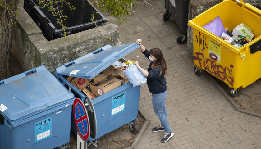 Kobieta wyrzucająca odpady do śmietników zewnętrznych
