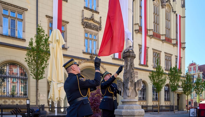 Żołnierz wciąga na maszt flagę Polski na wrocławskim Rynku