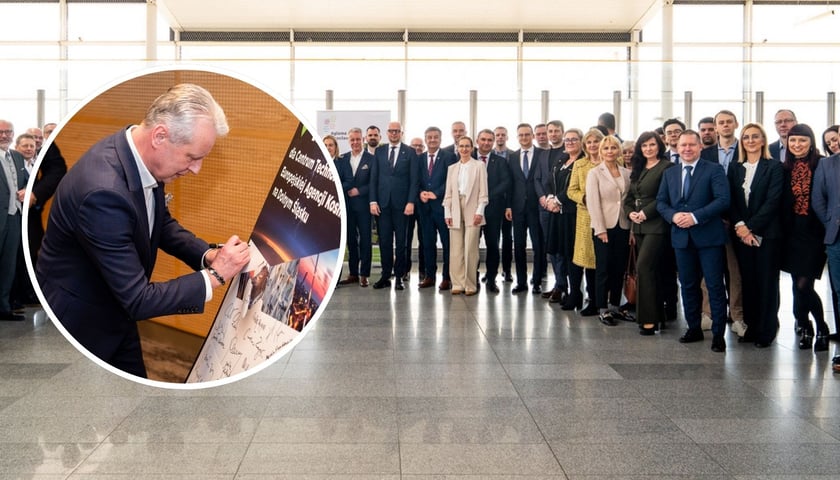 Zdjęcie przedstawiające uczestników spotkania stowarzyszenia Aglomeracja Wrocławska, po lewej w okrągłym kadrze mężczyzna składający podpis na tablicy "Tak dla Centrum Technologicznego Europejskiej Agencji Kosmicznej na Dolnym Śląsku".