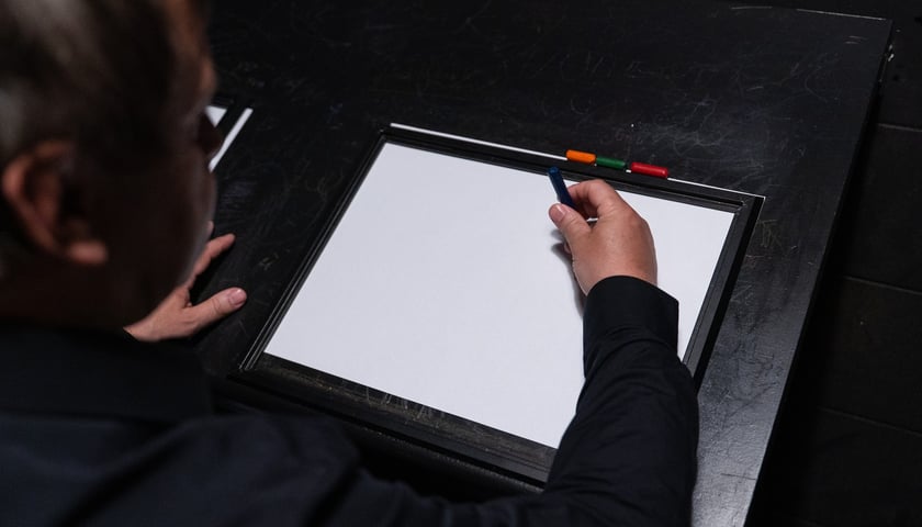 <p>Z wizytą w Niewidzialnym Domu we Wrocławiu. Na zdjęciu mężczyzna z kredką nad kartką papieru.</p>