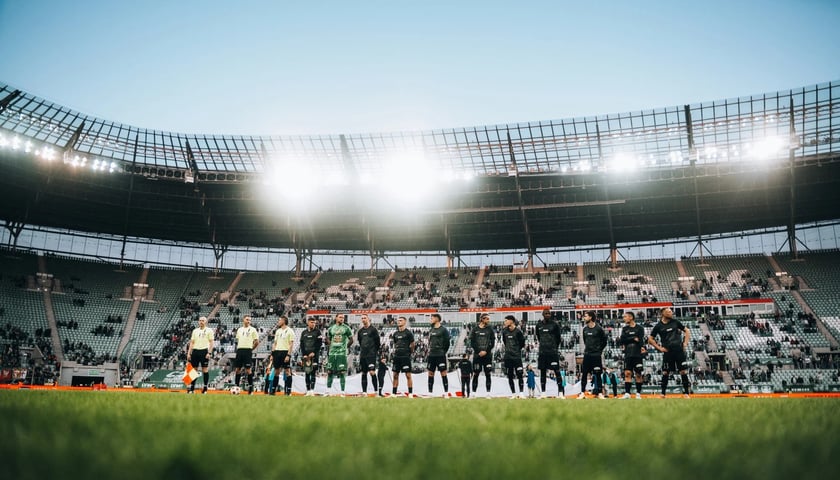 Piłkarze i sędziowie, w tle trybuny Stadionu Tarczyński Arena we Wrocławiu