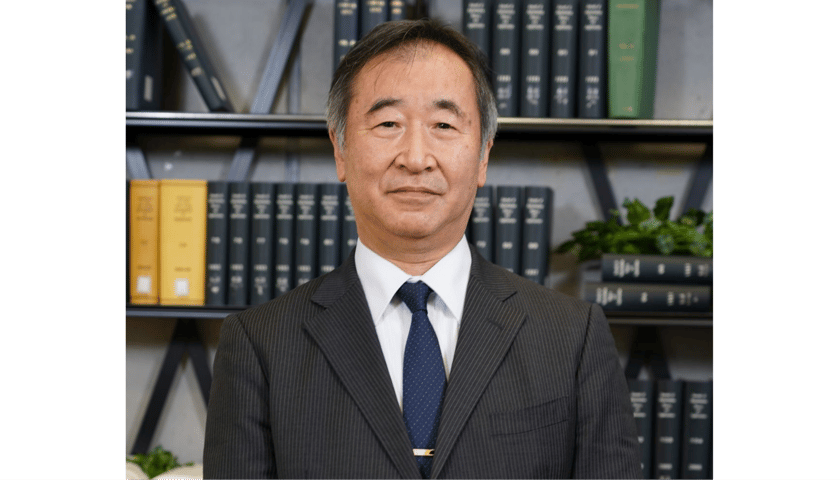 Prof. Takaaki Kajita. Zdjęcie przedstawia popiersie mężczyzny w garniturze, w tle regały z książkami.