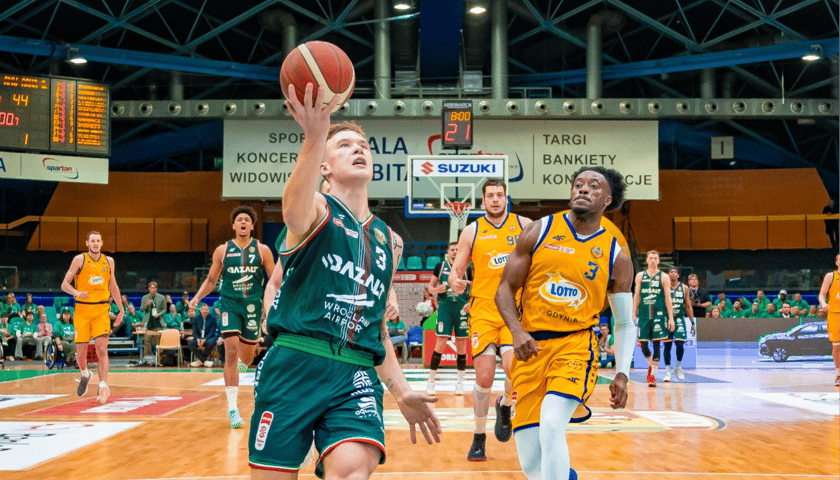 Zawodnik Śląska Wrocław tuż przed wyskokiem z piłka do kosza, w tle gracze Arki Gdynia - mecz fazy play-off 13 maja 2026 r.