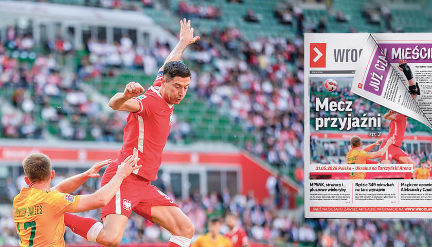Robert Lewandowski w czerwonym stroju sportowym wyskakujący do piłki. Po lewej stronie piłkarz drużyny Walii.