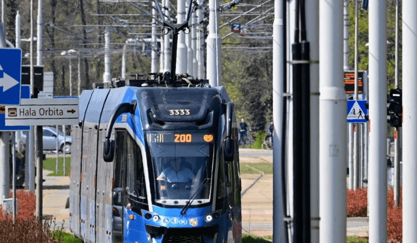 Niebieski tramwaj Moderus Gamma linii 19 jedzie ulicami miasta. Na jego przednim wyświetlaczu widnieje kierunek docelowy: ZOO