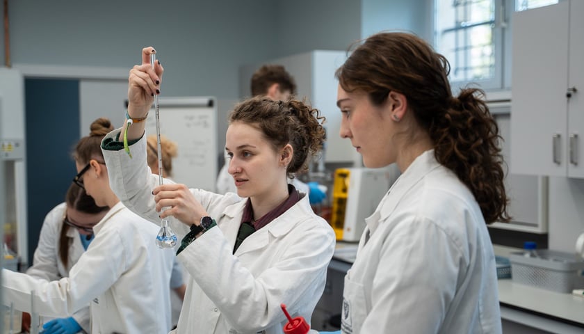 Studentki ubrane w białe fartuchy pracujące w laboratorium