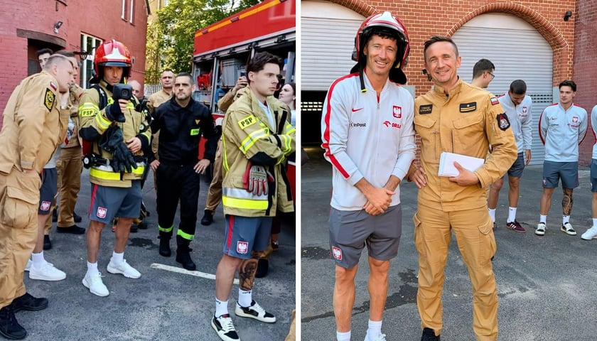 Grupa mężczyzn w jednostce straży pożarnej, w tle wozy strażackie. Robert Lewandowski i piłkarze reprezentacji Polski w Jednostce Ratowniczo-Gaśniczej nr 2 we Wrocławiu.  