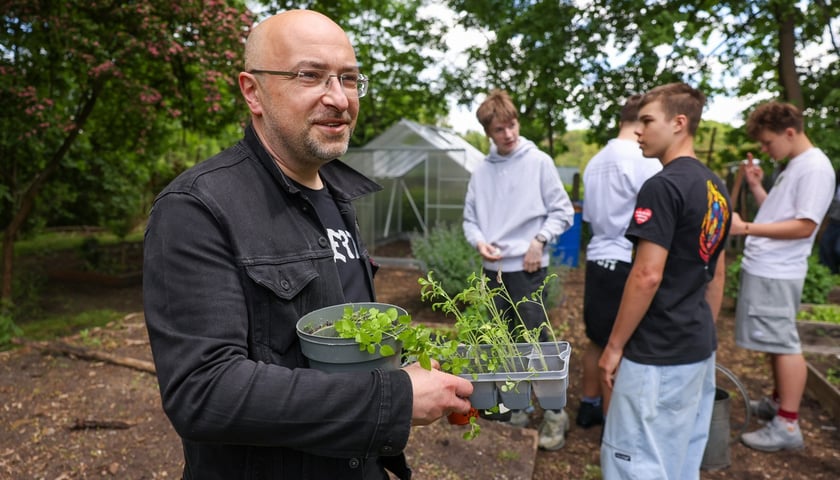 Tomasz Kulik, nauczyciel biologii z VI LO przy ul. Hutniczej na Pilczycach, pokazuje zioła, które też zostały zasadzone w ogrodzie. Na zdjęciu mężczyzna w okularach w zielonym otoczeniu
