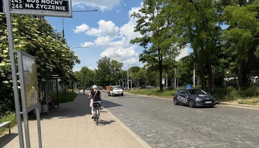 Rowerzystka jadąca chodnikiem i samochody przed skrzyżowaniem Borowskiej z Glinianą 