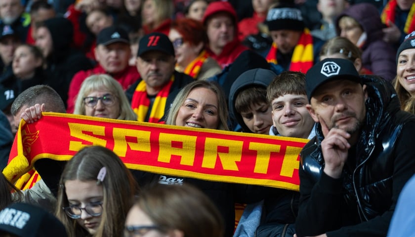 Na każdym meczu  Betard Sparty na stadionie Olimpijskim zasiada komplet kibiców. Na zdjęciu jedna z fanek trzyma szalik Sparty. Wokół niej inni kibice.