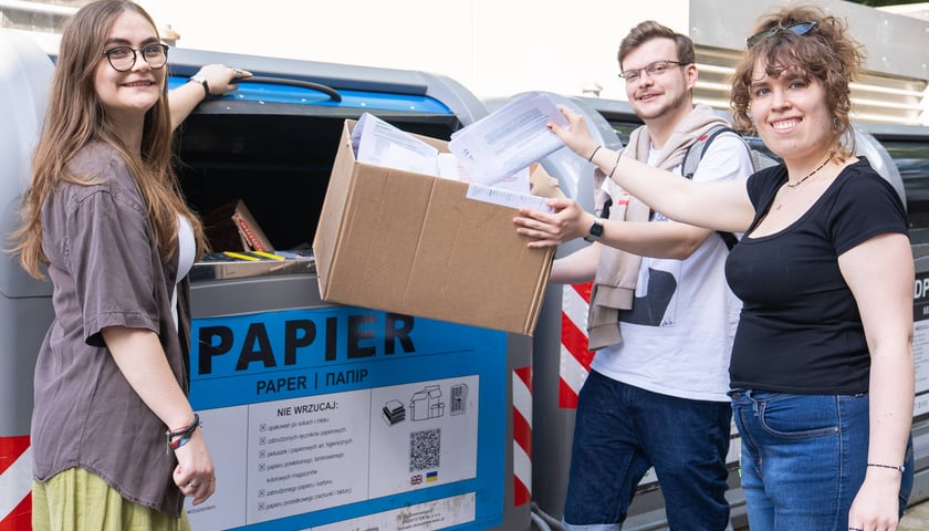 Troje studentów: Misia, Marcel i Irmina  wyrzucają stare notatki i kserówki do pojemnika oznaczonego na niebiesko z napisem "Papier"