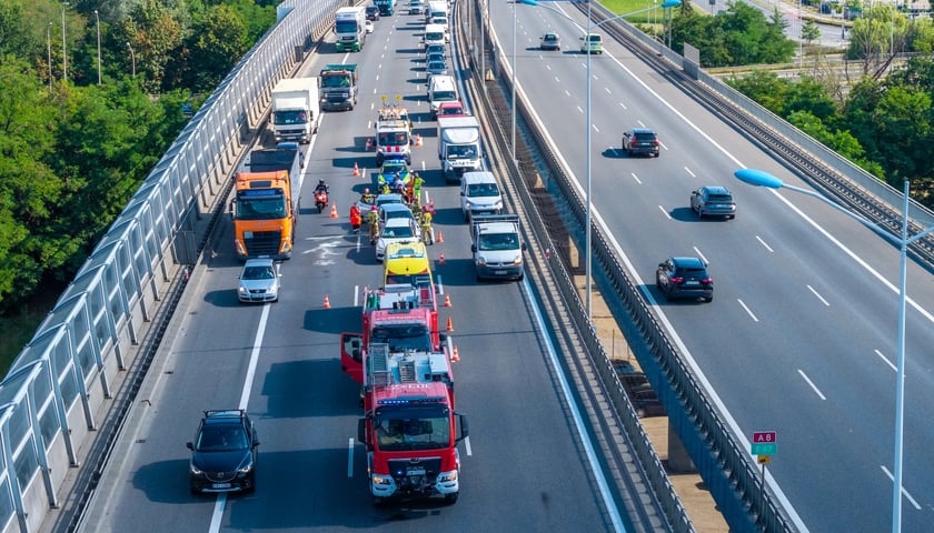 zdjęcie z drona: trzy rozbite samochody stoją na środkowym pasie AOW, interweniują policja, straż pożarna i pogotowie ratunkowe