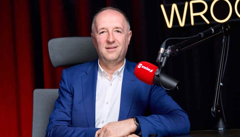 Mężczyzna obok mikrofon z napisem wroclaw.pl.. Robert Leszczyński, radny miejski.