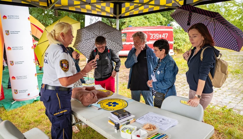 Piknik "Wakacje z Wroclaw.pl" pod wzgórzem Gajowym. Na zdjęciu stoisko Straży Miejskiej. Strażniczka rozmawia z kilkoma paniami