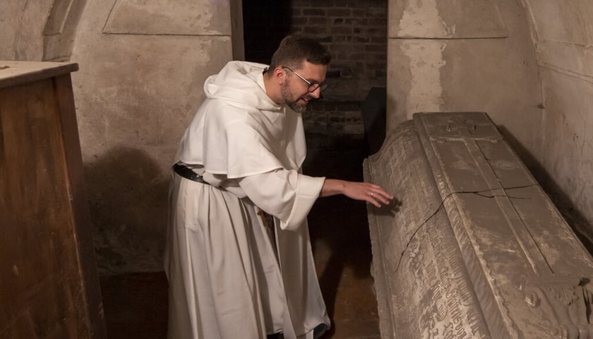Krypty pod kościołem dominikanów pw. św. Wojciecha we Wrocławiu. Na zdjęciu zakonnik pochyla się nad zabytkowym sarkofagiem