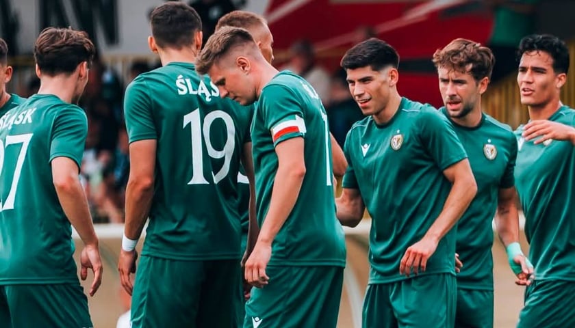 Zdjęcie ilustracyjne - grupa mężczyzn w zielonych strojach sportowych - piłkarze Śląska Wrocław na boisku.